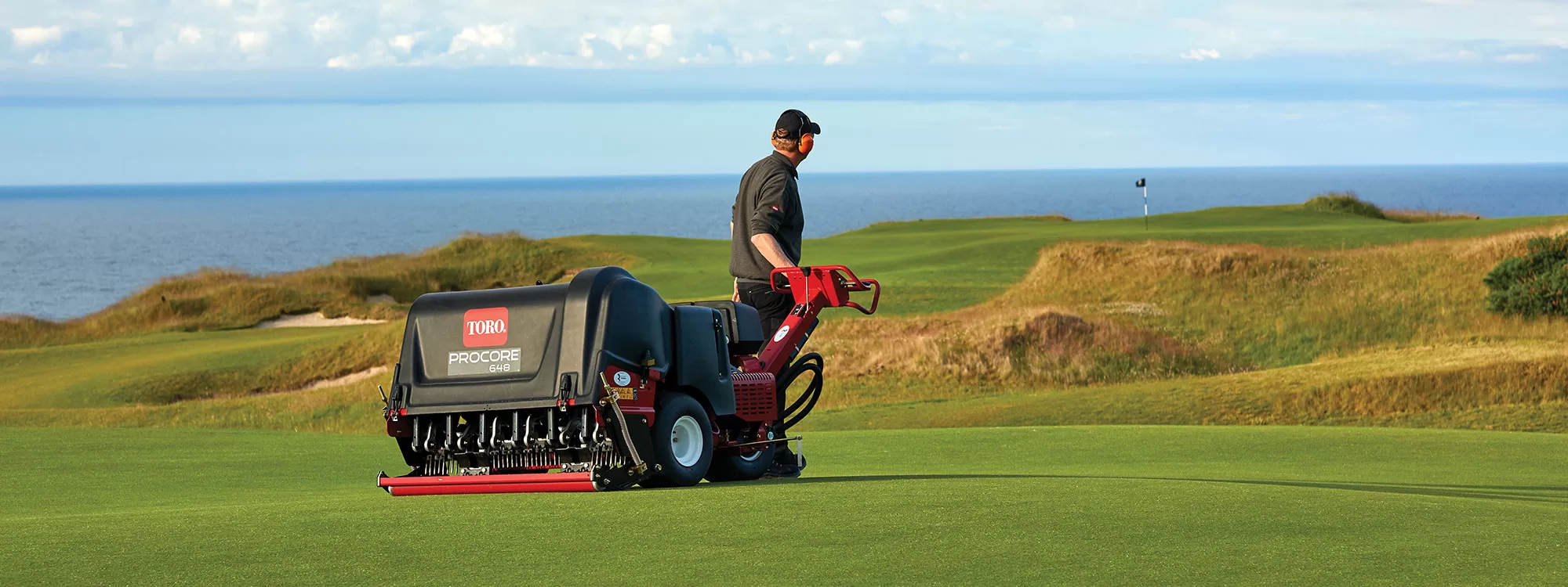 Aerator Pulled by Man on Golf Course